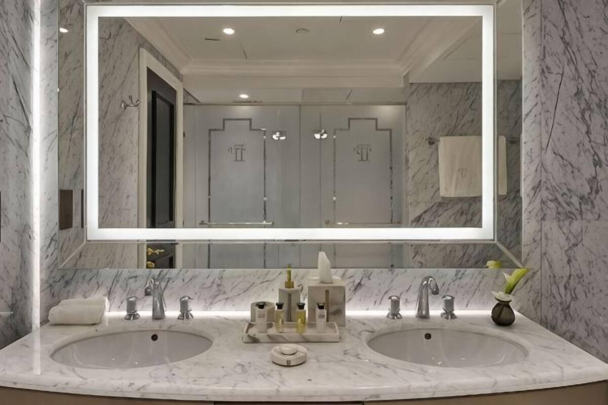 A bathroom with two sinks, a large mirror, and marble walls.