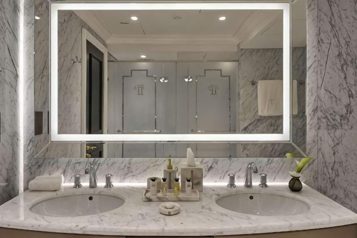Une salle de bain avec deux lavabos, un grand miroir et des murs en marbre.