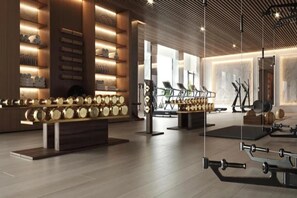 A modern gym with exercise equipment, wooden shelves with towels, and a large mirror. - The Plaza Doha, LXR Hotels & Resorts (DOHA)