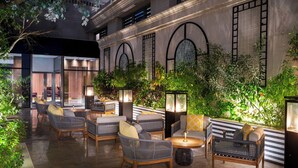 An outdoor seating area with wicker furniture, a coffee table, and a potted plant. - The Plaza Doha, LXR Hotels & Resorts (DOHA)
