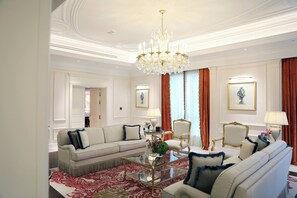 A spacious living room with a chandelier, a sofa set, a coffee table, and framed artwork on the walls. - The Plaza Doha, LXR Hotels & Resorts (DOHA)
