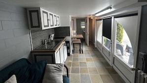 A compact kitchen with a sink, cabinets, and a window overlooking a garden. - Charmant Studio, à 1km de la Baie D'authie (Groffliers)