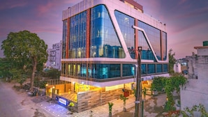 Un edificio moderno con amplios ventanales de vidrio, fachada curva y un área de entrada bien iluminada.