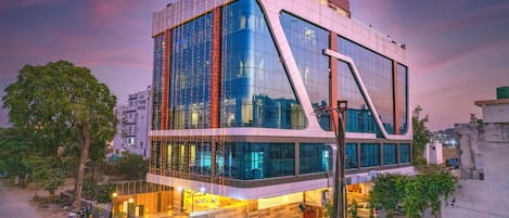 Un edificio moderno con amplios ventanales de vidrio, fachada curva y un área de entrada bien iluminada.