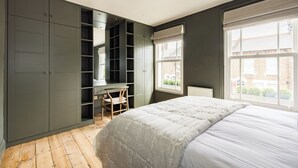 A bedroom with a bed, a desk, and built-in shelving. - The North Kensington Cottage No.2 (London)