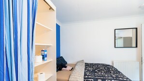 Une chambre à coucher avec un lit, une armoire, un radiateur et un miroir au mur.