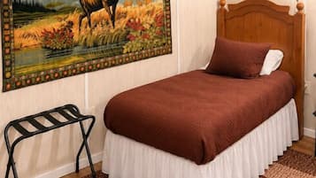 Un dormitorio con una cama, una mesita de noche, una lámpara, un cuadro de un ciervo y un cabecero de madera.