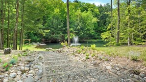 A forested area with a pond, a wooden pathway, and a small fountain. - Two cabins in one space. Enjoy your own private space in the cozy woods. Cabin is divided into two separate rooms. Dog friendly (Middle Grove)