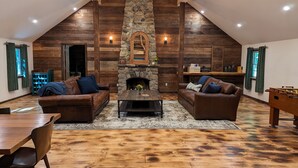 Una sala de estar acogedora con chimenea de piedra, paredes de madera y sofás de cuero.