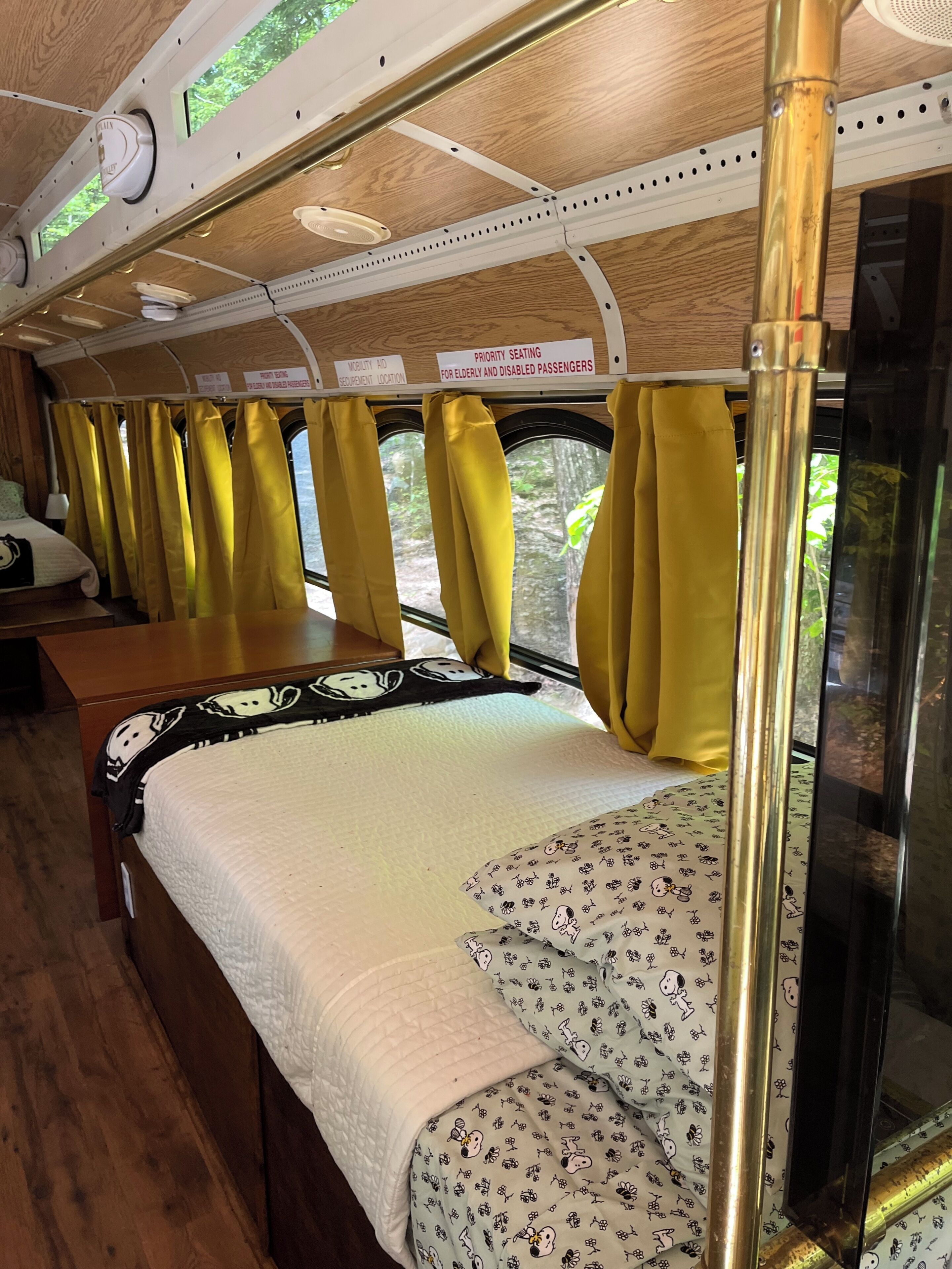 A train interior with a bed, yellow curtains, and signs indicating priority seating for elderly and disabled passengers.