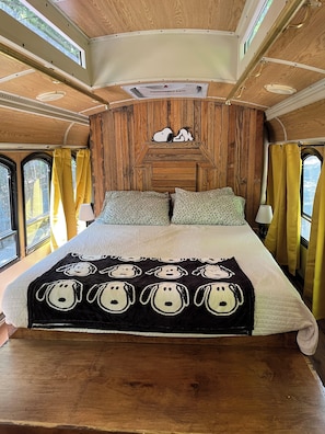 Un intérieur chaleureux avec un lit, des murs en bois et une fenêtre.