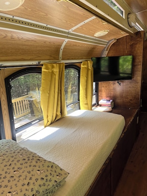 Ein Schlafzimmer mit Bett, Vorhängen, einem Fernseher und einem Fenster mit Blick.