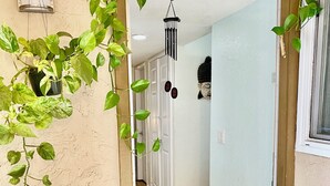 A doorway with a wooden floor, a potted plant on the left, and a hanging light fixture above. - Artsy home near Downtown and Balboa Park (San Diego)
