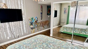 A bedroom with a large mirror, a patterned bedspread, and a mural of animals on the wall. - Artsy home near Downtown and Balboa Park (San Diego)