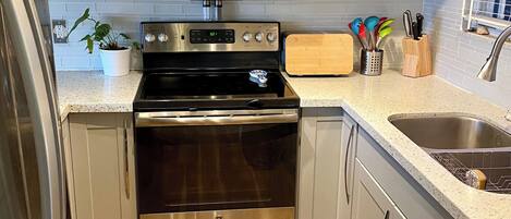 Una cocina compacta con electrodomésticos de acero inoxidable, incluyendo un microondas, horno y refrigerador.