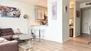 A modern living room with a glass coffee table, a sofa, and a kitchen in the background. - Artsy home near Downtown and Balboa Park (San Diego)