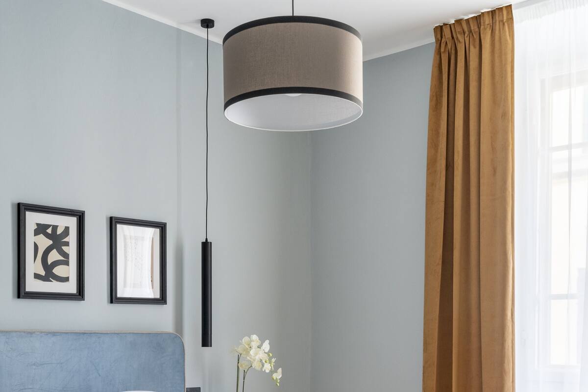 A modern bedroom with a large bed, a bedside table with a lamp, and a window with curtains.