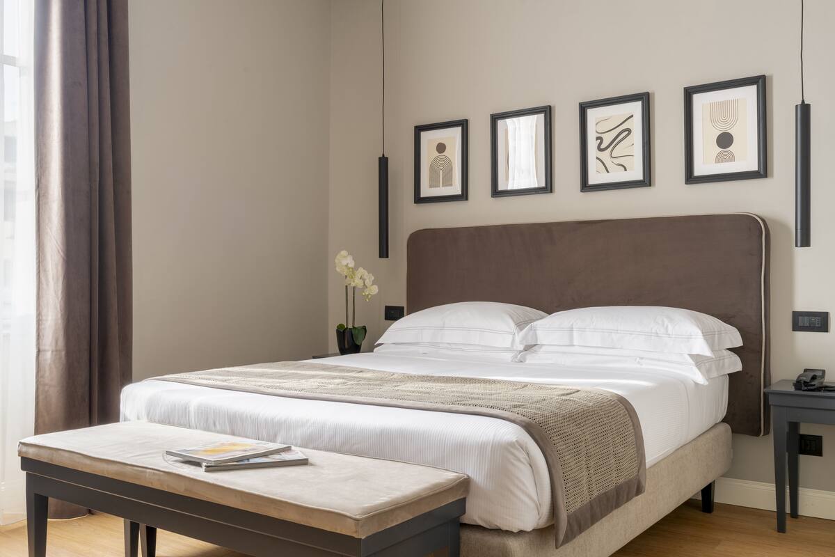 A neatly arranged bedroom with a large bed, a bedside table, and a wall-mounted artwork.