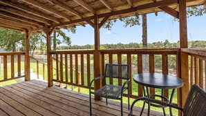 Une terrasse en bois dotée d’un espace abrité, comprenant une table et deux chaises.