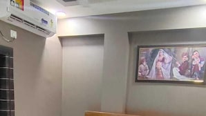 Un dormitorio con cama de madera, ropa de cama blanca, ventilador de techo, equipo de aire acondicionado y un cuadro en la pared.