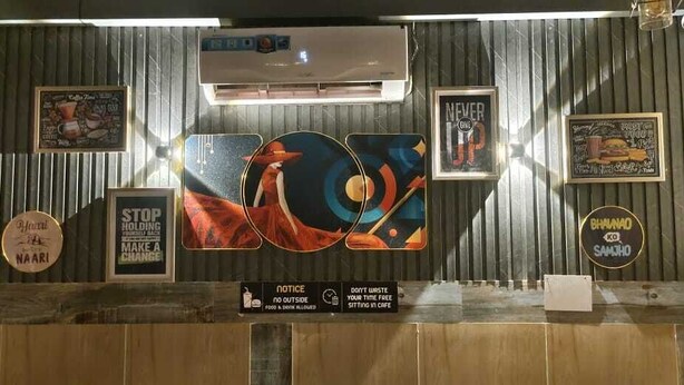 Un mostrador de recepción de diseño moderno, con una obra de arte grande, varios carteles y una pantalla digital.