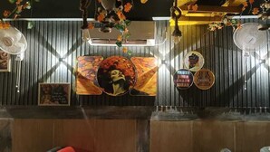 Una zona de recepción con mostrador de madera, ventiladores en la pared y varias fotografías y carteles enmarcados.