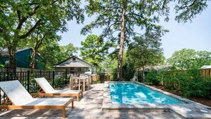 Un espace piscine avec des chaises longues, une terrasse en bois et un jardin clôturé.