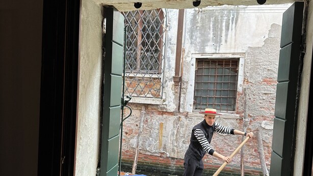 A window with a view of a narrow alleyway and a person cleaning the window. - Sofia's canal-side mansion in San Stae luxury apartment with canal view (Venezia)