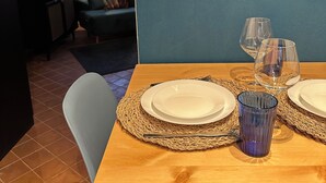 A dining area with a wooden table set for two, two wine glasses, and a blue glass pitcher. - Sofia's canal-side mansion in San Stae luxury apartment with canal view (Venezia)