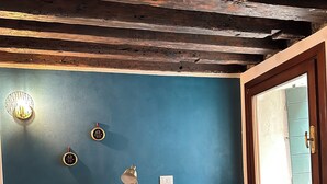 A room with a teal sofa, a small table with decorative items, a wall clock, and a window with a view. - Sofia's canal-side mansion in San Stae luxury apartment with canal view (Venezia)