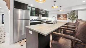A modern kitchen with stainless steel appliances, a central island, and pendant lighting.