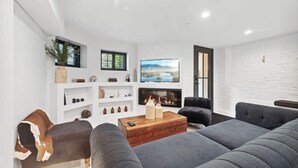 A modern living room with a fireplace, grey sofas, and a large TV.
