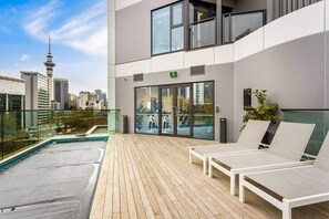 Een terras op het dak met loungezetels, een houten terras en uitzicht over de stad.