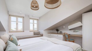 Une chambre avec un grand lit, un bureau et une fenêtre donnant sur des immeubles.