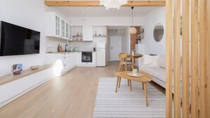 Une cuisine moderne avec des meubles blancs, un four encastré et un grand téléviseur à écran plat.
