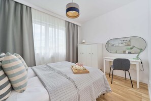 Quarto com cama, escrivaninha, cadeira, guarda-roupa e luminária suspensa.
