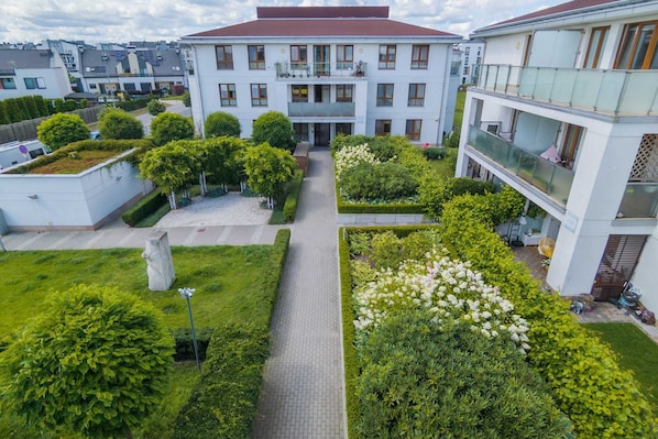 Un immeuble à plusieurs étages doté d’une cour intérieure, entouré de verdure et bordé d’une allée pavée.