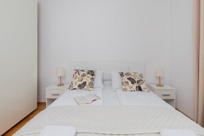 Une chambre à coucher bien rangée, avec un lit, deux tables de chevet et une petite table de nuit.