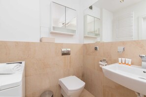 Un baño moderno con inodoro, lavamanos y perchero para toallas.