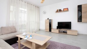 Un salon moderne avec un canapé, une table basse, un téléviseur et des meubles en bois.