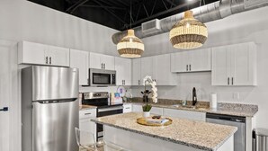 A modern kitchen with stainless steel appliances, white cabinetry, granite countertops, and pendant lighting. - Modern Loft · Pet Friendly · 8 Min BNA · Fast WiFi (Nashville)
