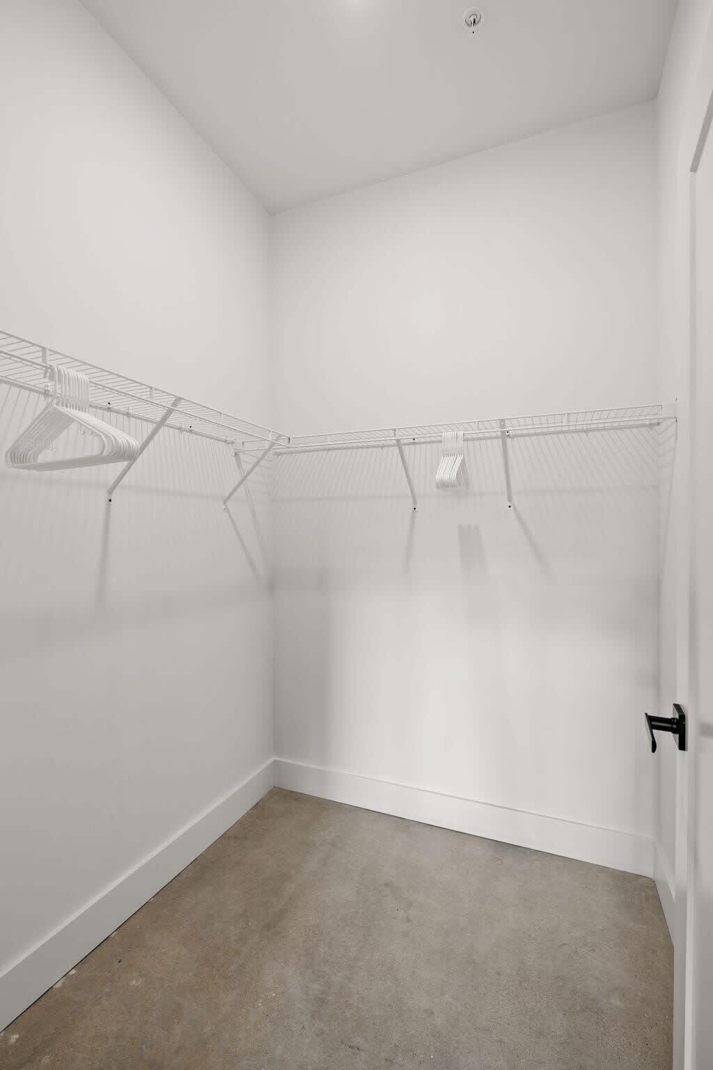 Un petit dressing vide, avec une étagère en métal et une porte.