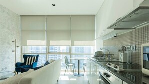Une cuisine moderne avec une grande fenêtre, un coin repas avec une chaise bleue et un canapé.