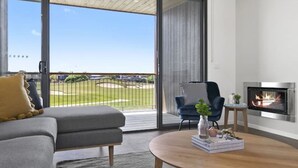 A modern living room with a grey sofa, a blue armchair, and a fireplace.