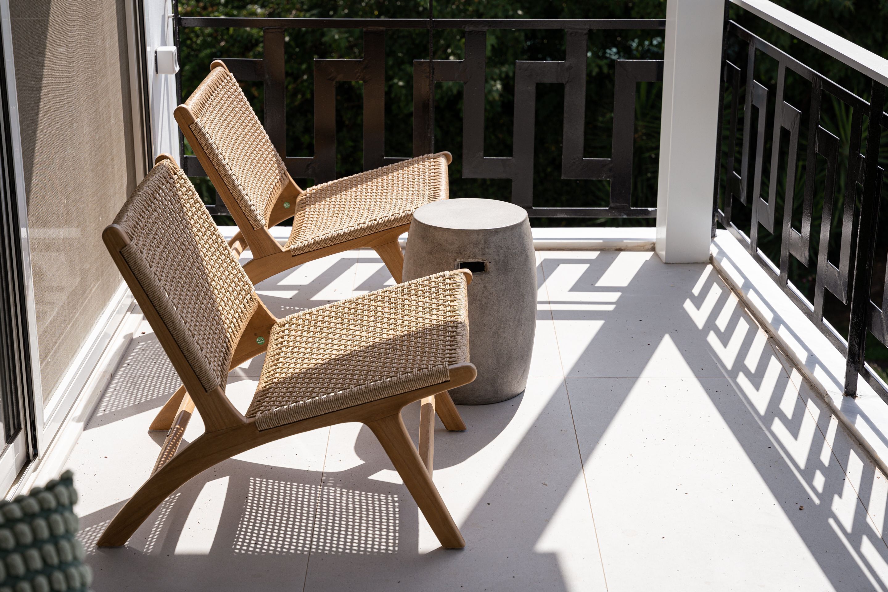 A balcony with two wicker chairs and a round table.