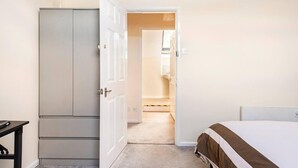 Une chambre à coucher avec un lit, une armoire et une salle de bain visible à travers une porte ouverte.