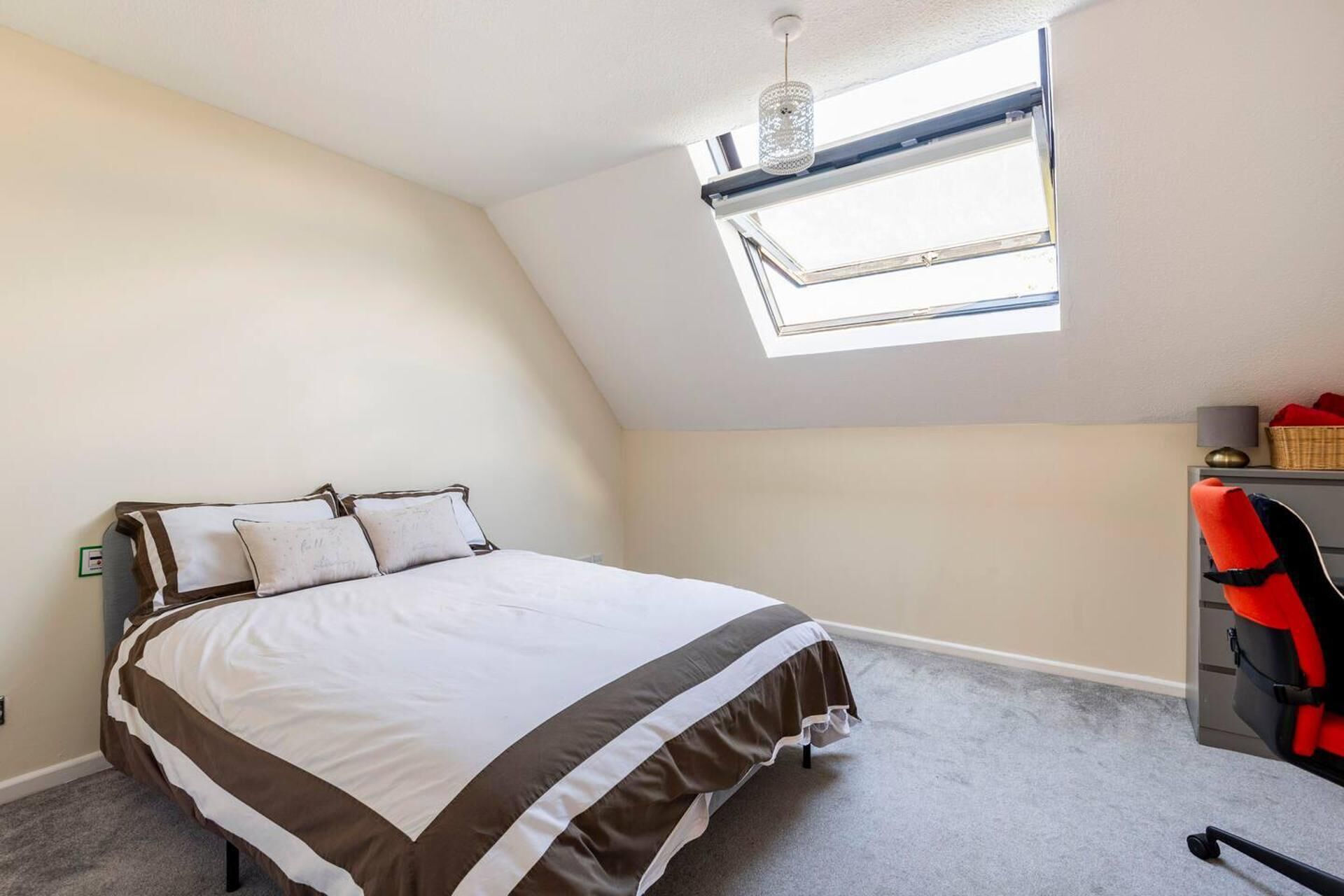 A bedroom with a bed, a desk, and a window.