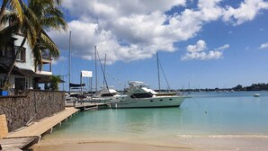 Ein Yachthafen mit vertäuten Yachten, ein Strand und ein Gebäude mit einer Steinmauer.