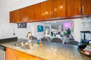 A kitchen with granite countertops, wooden cabinets, and a dining area with chairs and a table. - Brickell Bay retreat w/ balcony & year-round pool (Miami)