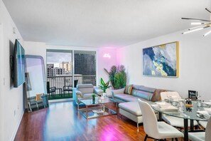 A modern living room with a sofa, coffee table, and dining area. - Brickell Bay retreat w/ balcony & year-round pool (Miami)